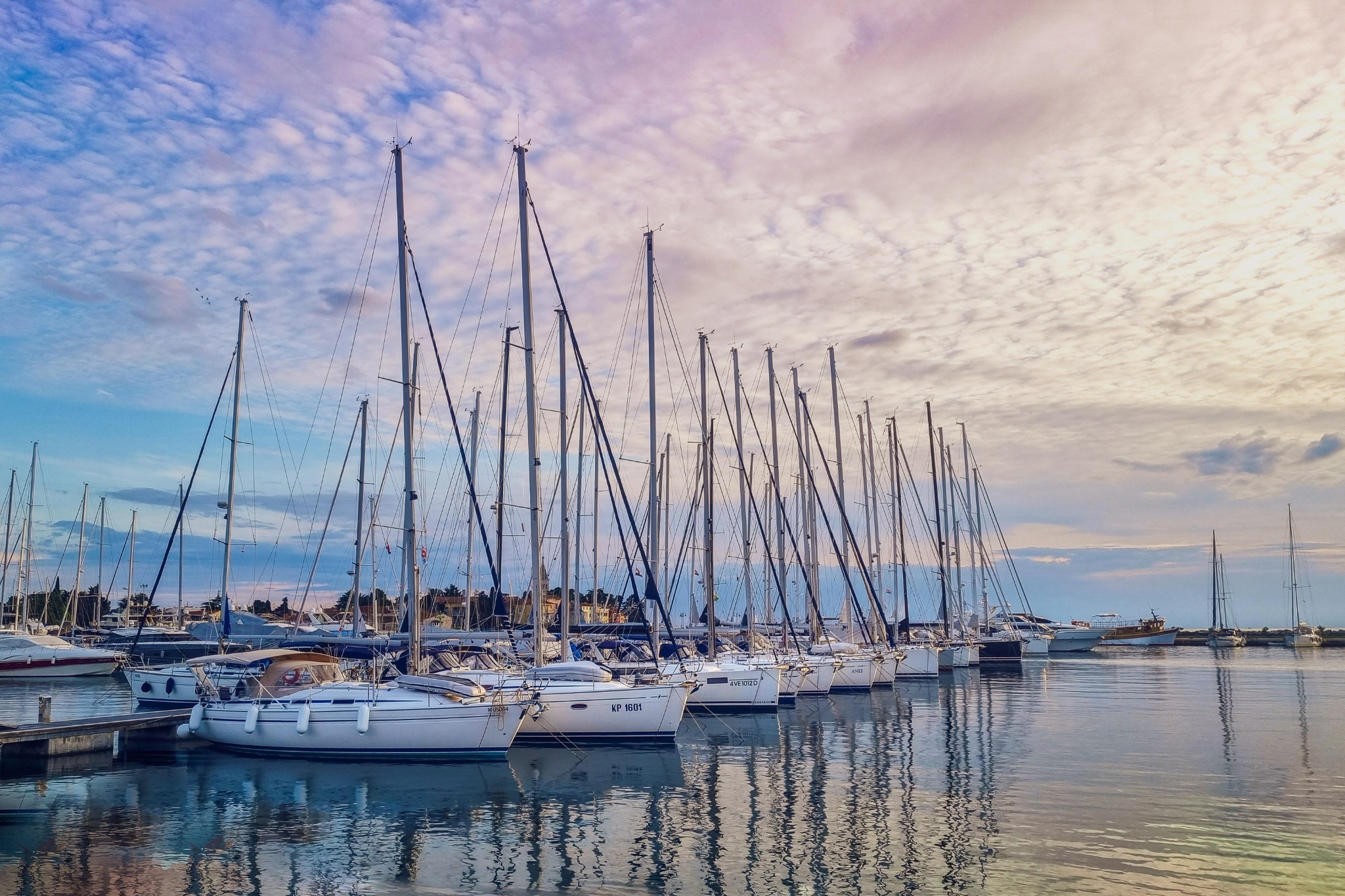 Barche a vela ormeggiate in una marina sotto un cielo dalle sfumature azzurre e rosate